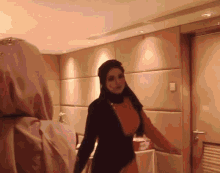 a woman in a hijab stands in a room