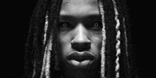 a close up of a person 's face with dreadlocks .