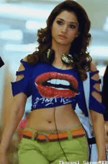 a woman wearing headphones and a blue crop top with a picture of a mouth on it .