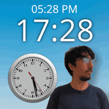 a man stands next to a clock that says 17:28 pm