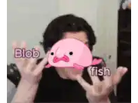 a man holding a pink blob fish in front of his face