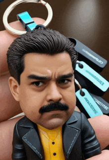 a figurine of a man with a mustache is holding a keychain