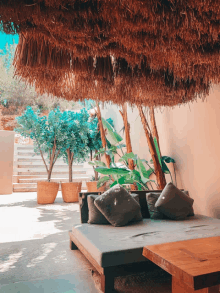 a patio with a thatched umbrella over a bed and table