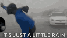 a person in a blue jacket is standing in the rain with a car in the background .