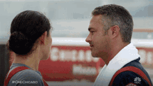 a man and a woman are looking at each other in front of a sign that says chicago on it