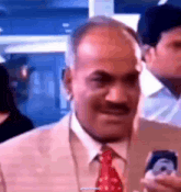 a man in a suit and tie is smiling and holding a piece of paper in his hand