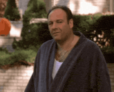 a man in a bathrobe stands in front of a house