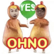 two people in chicken costumes are holding a green balloon and dancing .