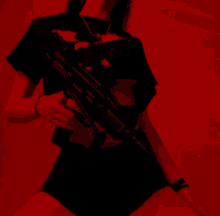 a woman in a black shirt is holding a gun in her hand in a red light .