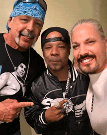 three men are posing for a picture with one wearing a shirt that has a picture of a man on it