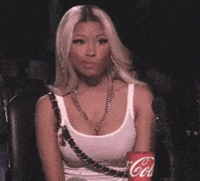 a woman is sitting in a chair with a coca cola can in her hand .
