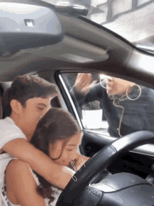 a boy and a girl are hugging in a car with the word friends written on the side of the car