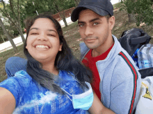 a man and woman are posing for a picture and the woman is wearing a face mask