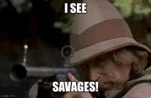 a man in a hat is holding a rifle and says `` i see savages '' .