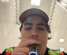 a man is brushing his teeth in a bathroom while wearing a hat