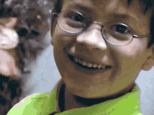 a boy wearing glasses and a neon green shirt smiles