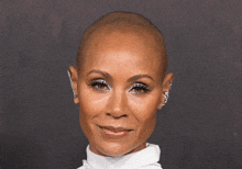 a close up of a woman 's face with a shaved head and earrings