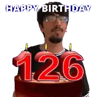 a man with glasses is holding a birthday cake with candles in the shape of the number 126