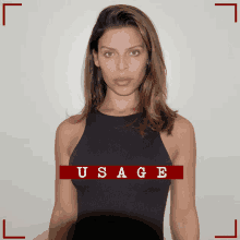 a woman in a black tank top stands in front of a red usage sign