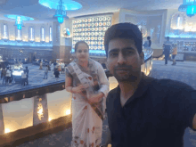 a man and a woman are posing for a picture in front of a wall that says ' 000000 ' on it