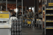 a woman pushing a shopping cart in a grocery store with a sign that says ' coca cola ' on it