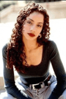 a woman with curly hair is wearing a black sweater and jeans