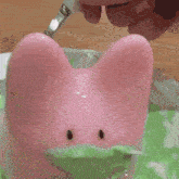 a person is painting a pink bunny with a brush