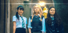 three girls in school uniforms are standing next to each other in front of a building .