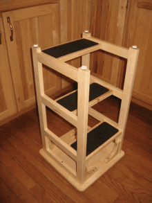 a wooden stool with three steps sits on a wooden floor in front of a wooden cabinet