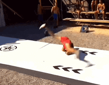 a man in a red shirt is doing a handstand on a white surface with arrows pointing in opposite directions