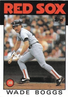 wade boggs is a red sox baseball player holding a bat on a baseball field .