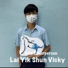 a man wearing a mask holds a sign that says vice chairperson lai yik shun vicky