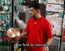 a man in a red shirt is standing in front of a display of kitchen utensils and says ye fenk ke marunga