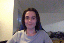 a man with long hair is smiling and wearing a gray shirt