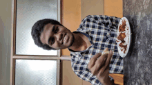 a man in a plaid shirt is sitting at a table with a plate of food