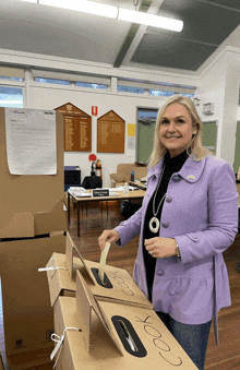 a woman in a purple coat is putting a ballot in a box that says cook on it