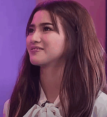 a close up of a woman 's face with long hair and a white shirt .