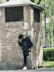 a man leaning against a stone wall wearing a hoodie that says ' king ' on it