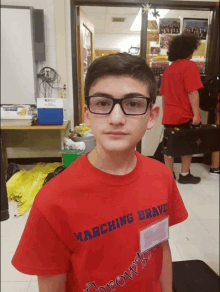 a young boy wearing glasses and a red marching brave shirt