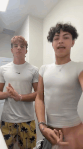 two young men standing next to each other in front of a mirror .