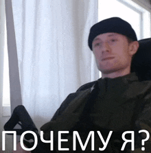 a man in a black hat is sitting in front of a window with the words " почему я " on the bottom