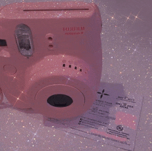 a pink fujifilm instax mini 3 camera sits on top of a ticket