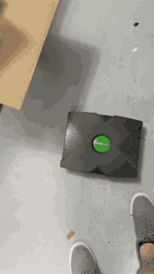 a black xbox with a green button on the top