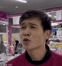 a man in a red jacket is making a funny face in a toy store .