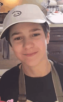 a young boy wearing a white hat and an apron is smiling