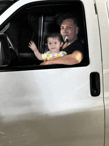 a man smoking a cigarette while holding a baby in his car