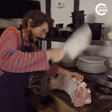 a man in an apron is cutting a piece of meat on a cutting board with meilleur bon written on the bottom