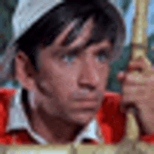 a man wearing a baseball cap and a red shirt is holding a sword .