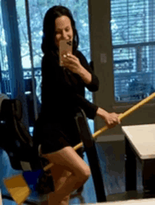 a woman is taking a picture of herself in the mirror while holding a mop .