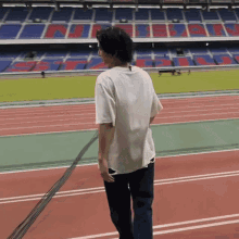 a man in a white shirt is standing on a track in front of an empty stadium with the word nissan on the stands